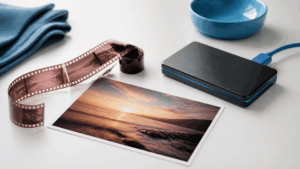 35mm film negative and printed photograph beside an external hard drive on a white surface